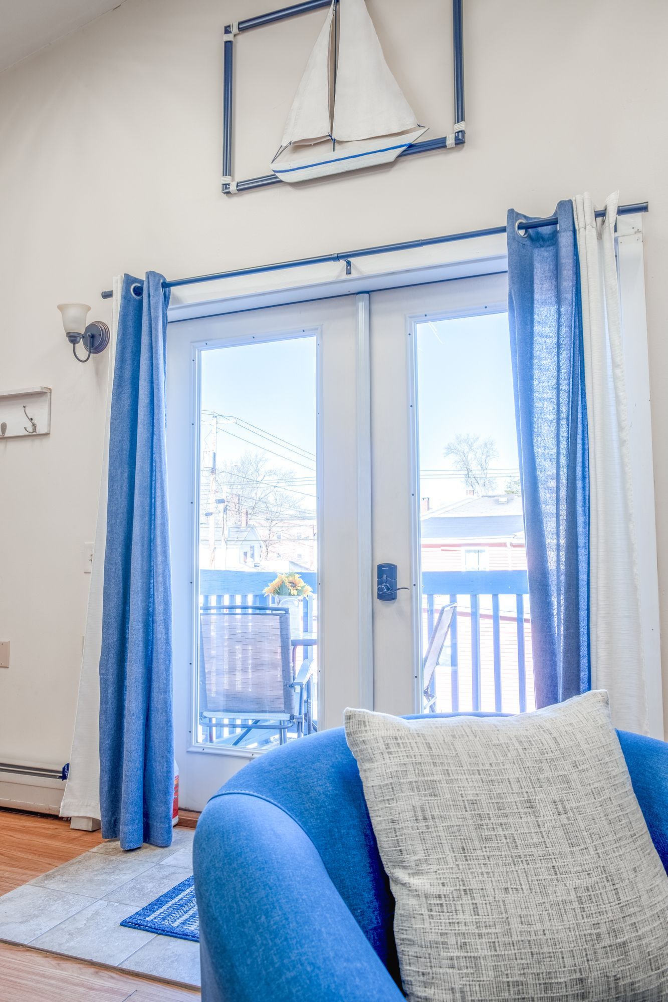 A living room with a blue chair and a sailboat on the wall.