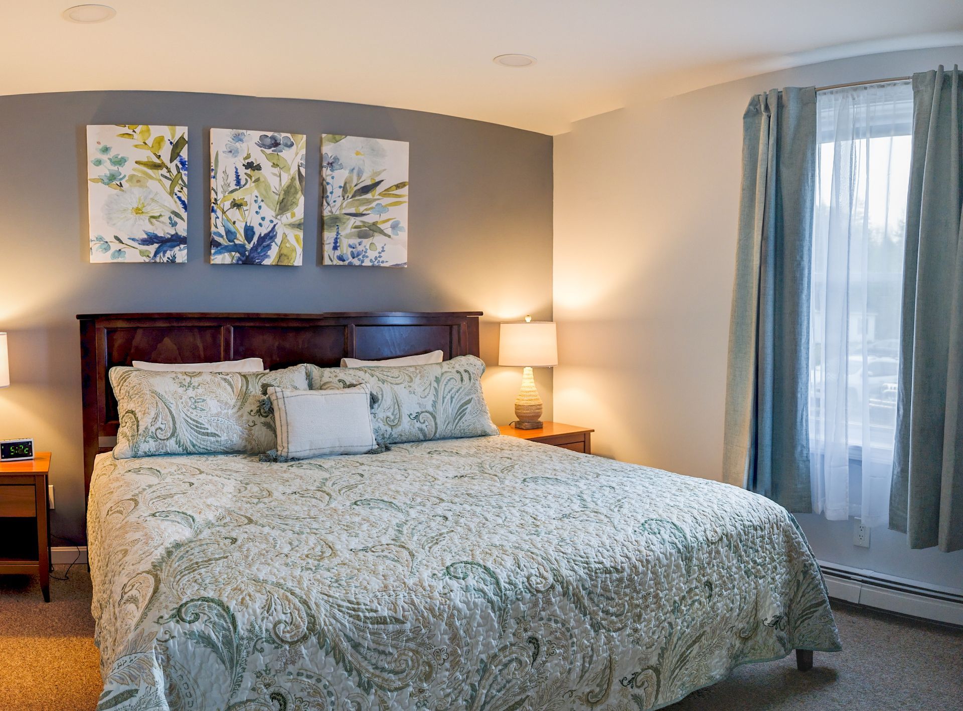A bedroom with a king size bed and three paintings on the wall.