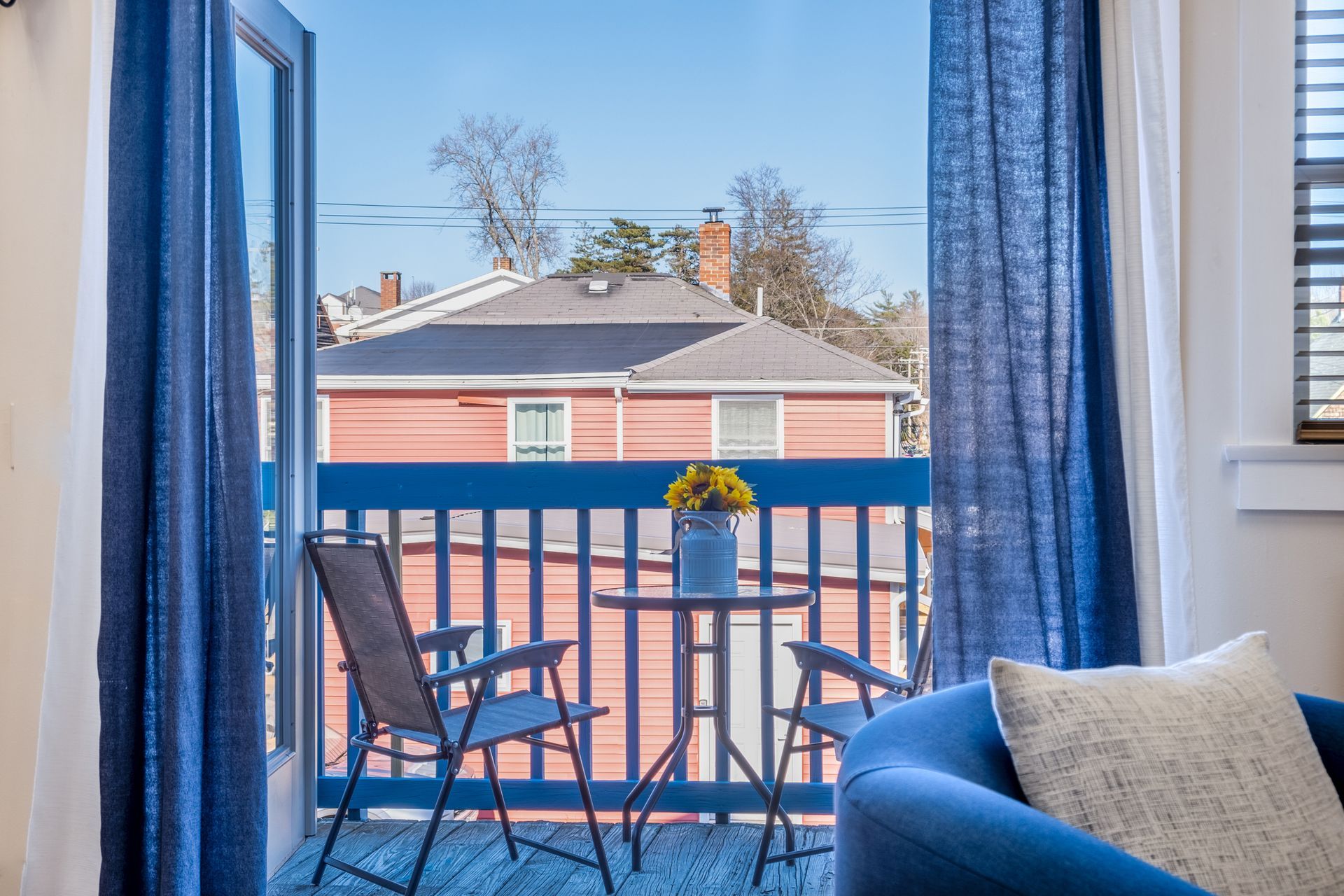 A balcony with a table and chairs and a view of a house.