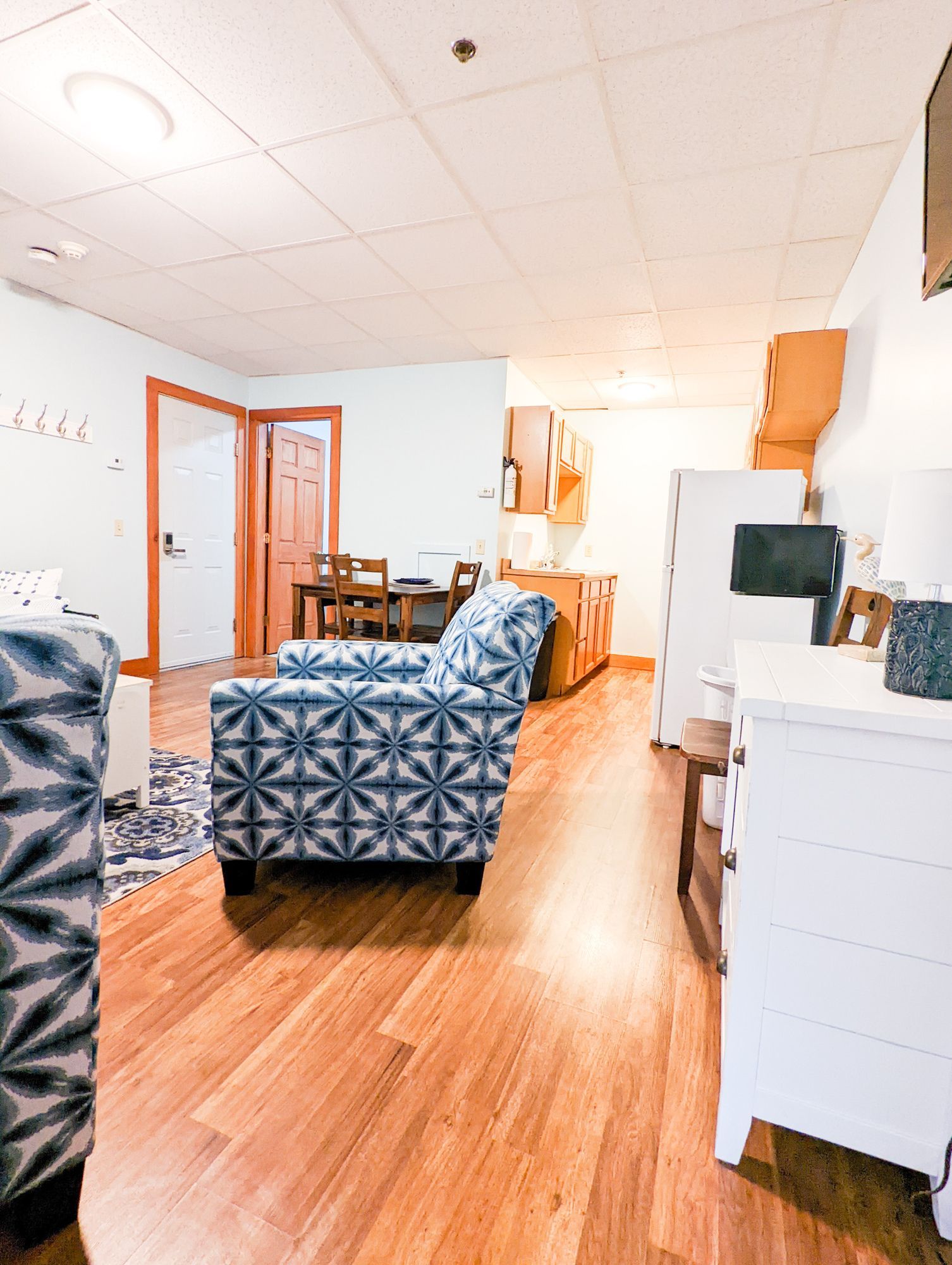 A living room with hardwood floors , a couch , chair and dresser.