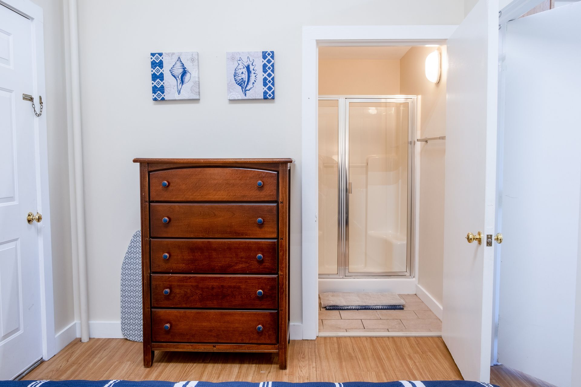 A bedroom with a dresser and a walk in shower.