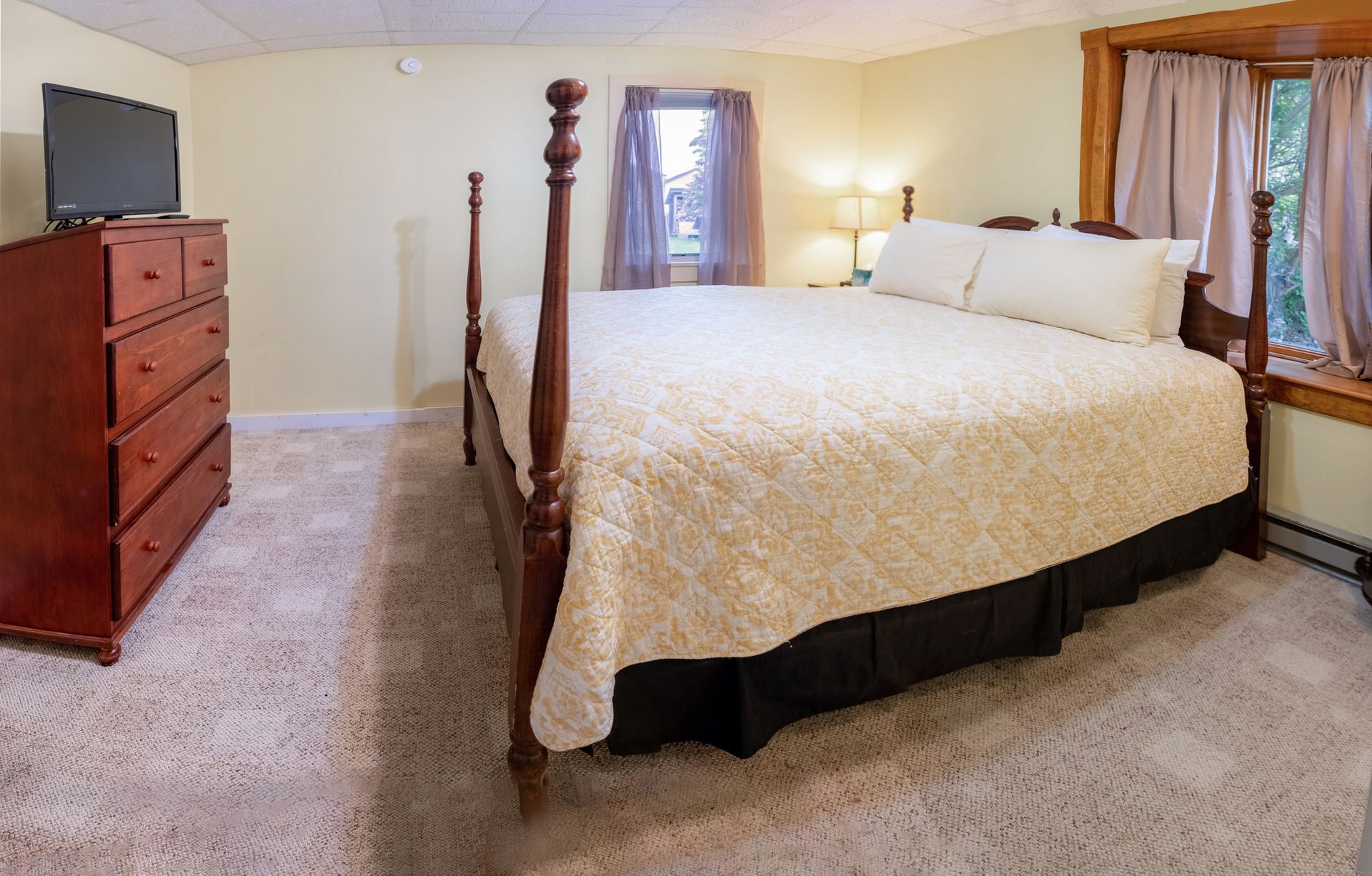 A bedroom with a king size bed , dresser , and television.