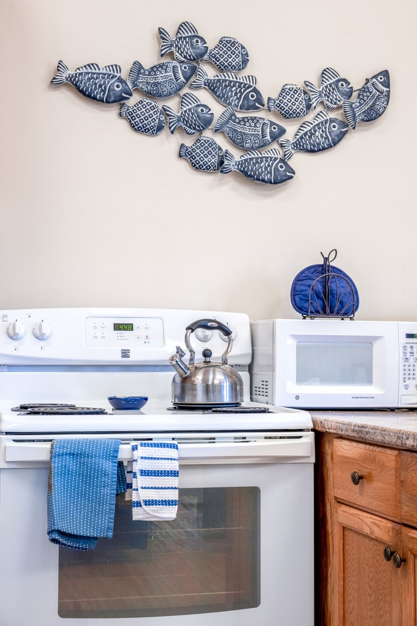 A kitchen with a stove , microwave , and kettle.