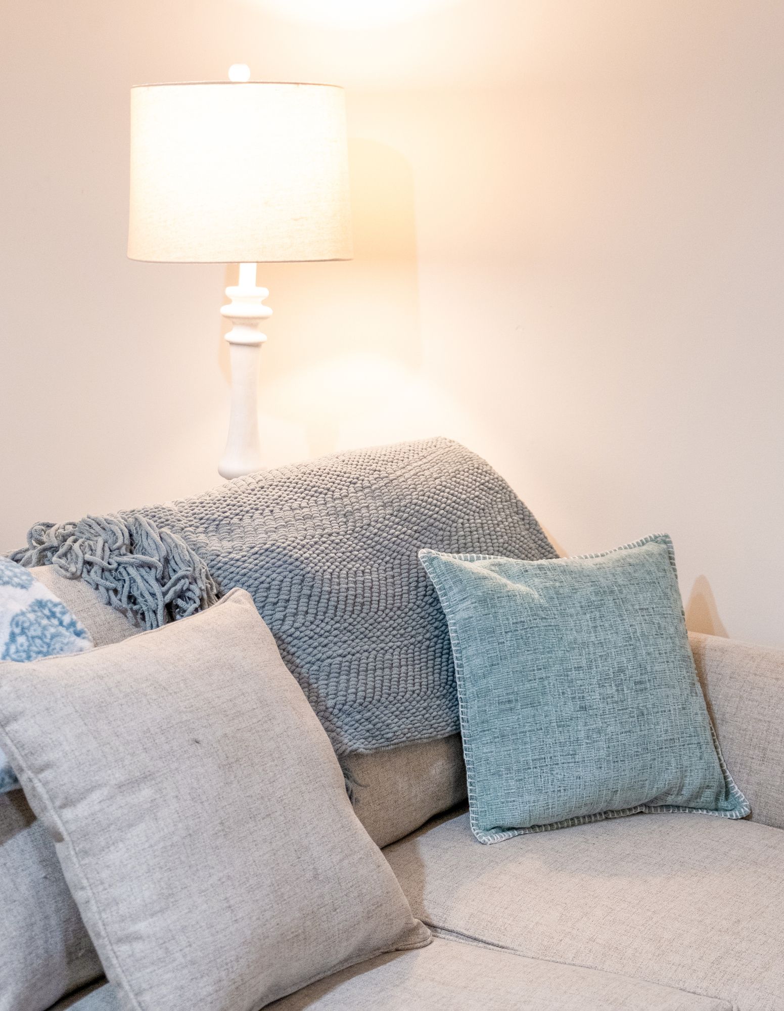 A couch with pillows and a lamp in a living room.