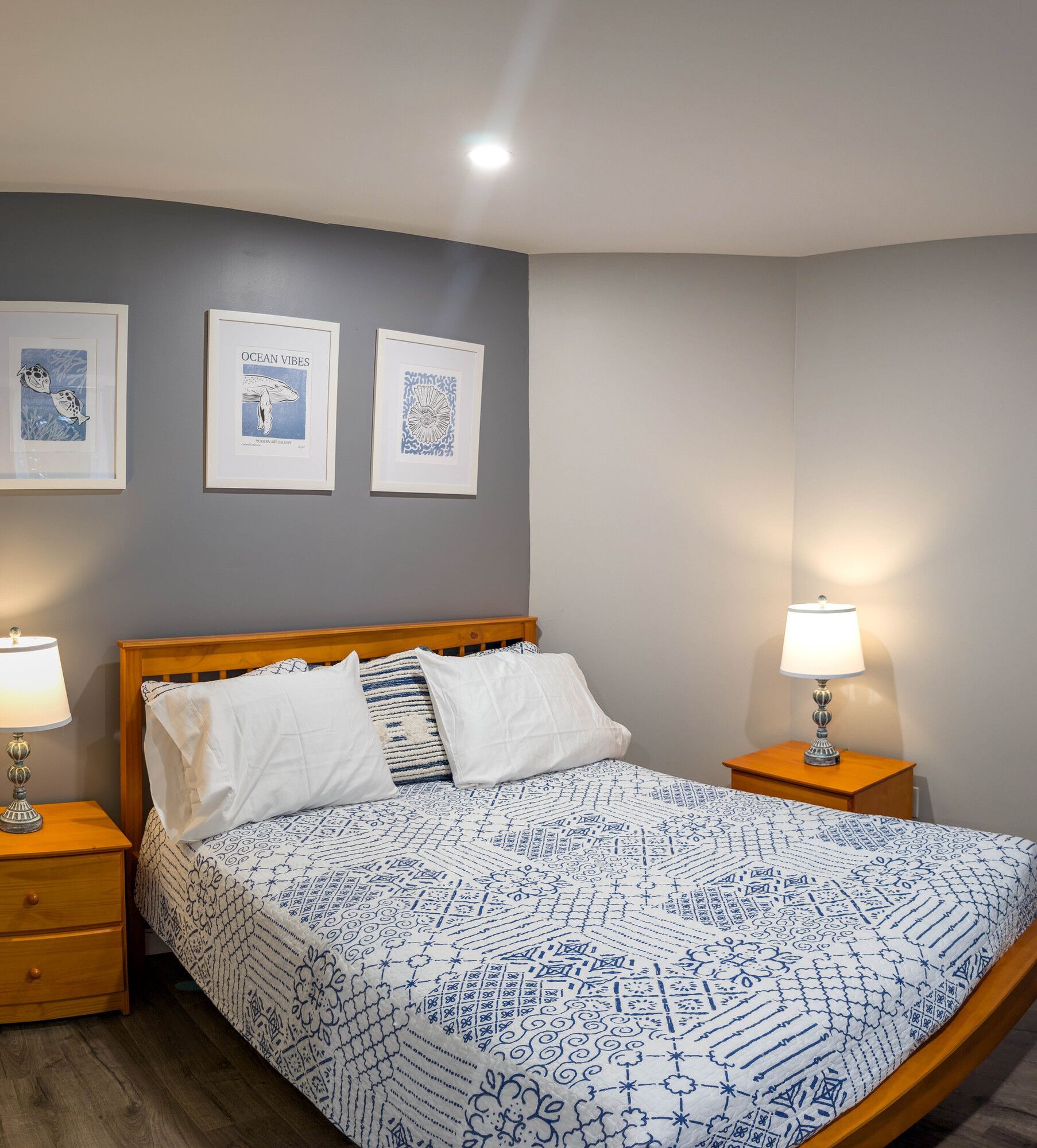 A bedroom with a bed lamps and pictures on the wall