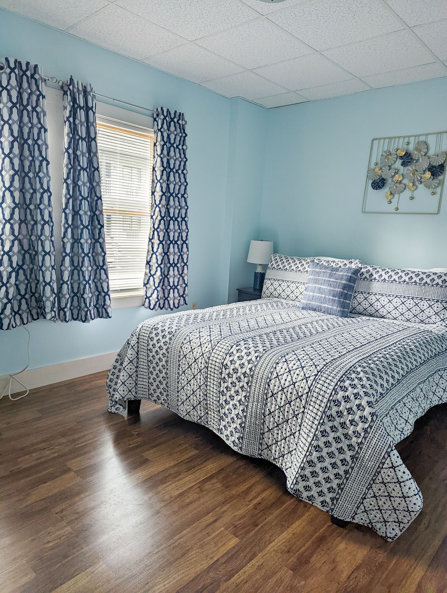 A bedroom with a bed , two windows and a lamp.