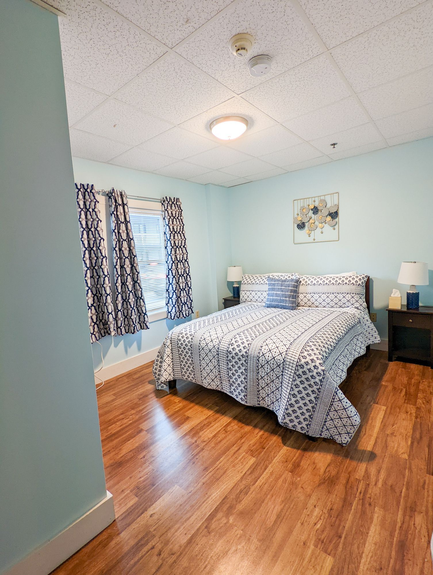 A bedroom with a bed , two nightstands , and two windows.