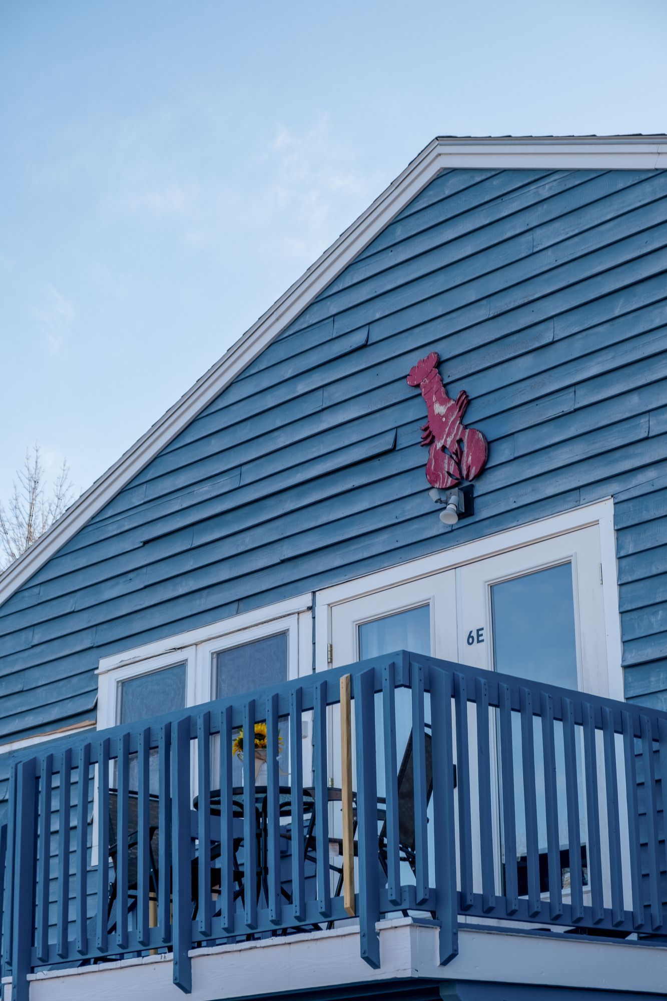 A blue house with a balcony and a red sign on the side.