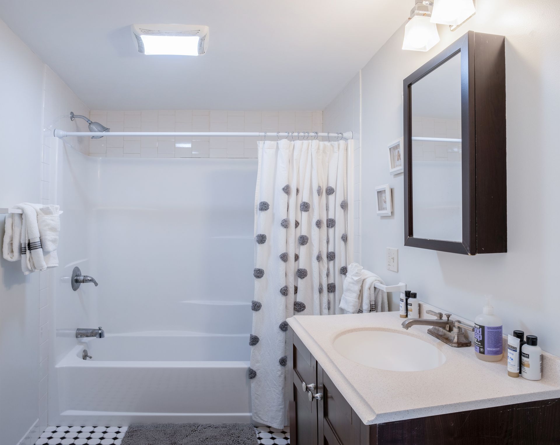 A bathroom with a sink , tub , shower and mirror.