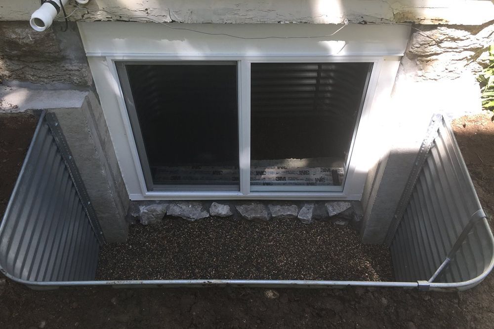 A window in a basement with a metal fence around it.