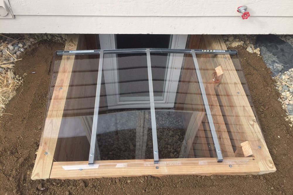 A window well is being built under a house.