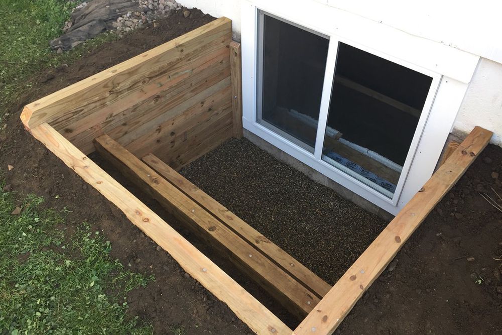 A window well in a basement with a wooden frame around it.