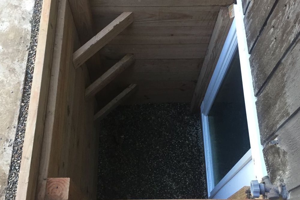 A hole in a wall with a window and stairs leading up to it.