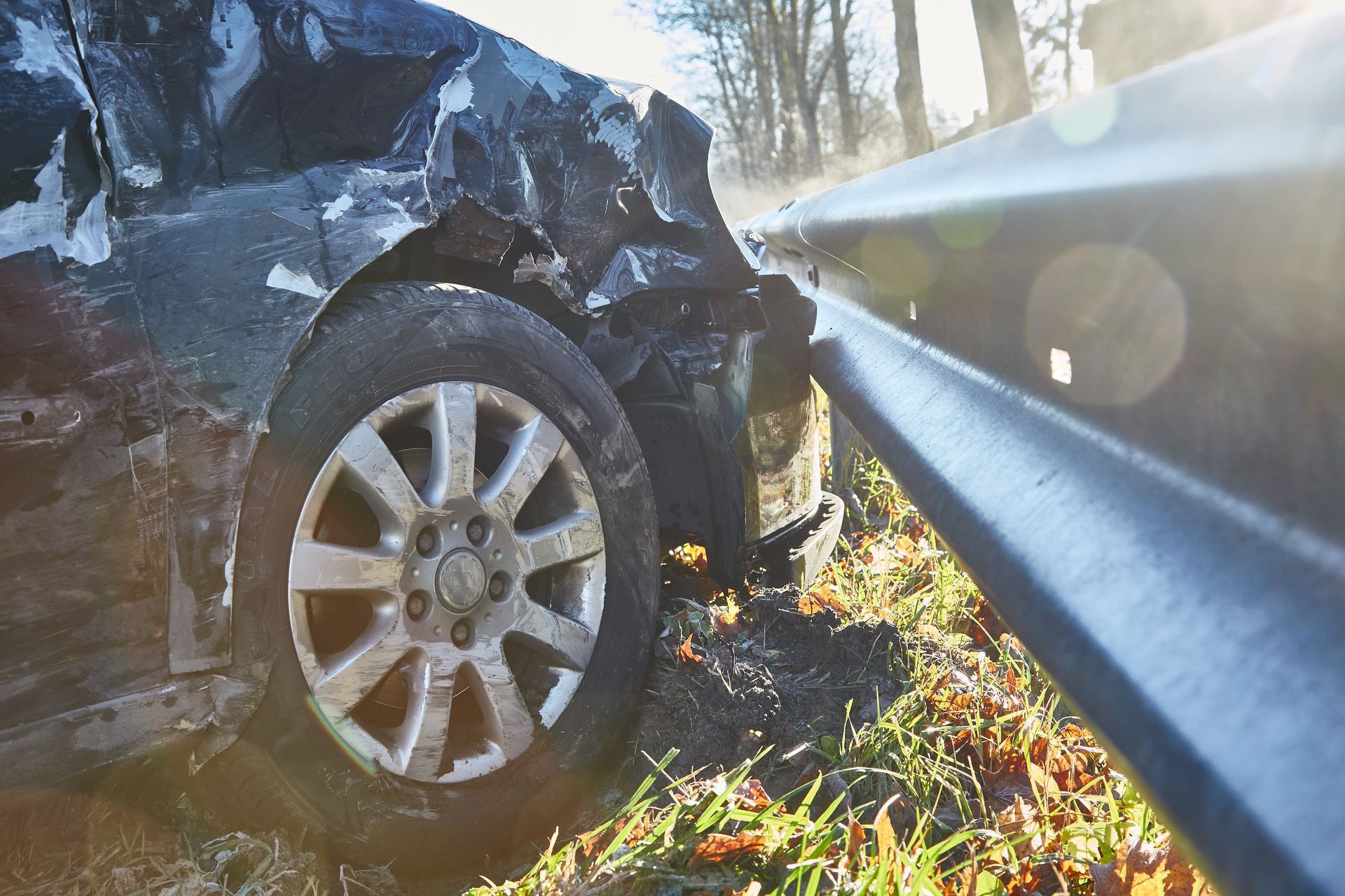Une voiture endommagée lors d'un accident est garée à côté d'une barrière routière.