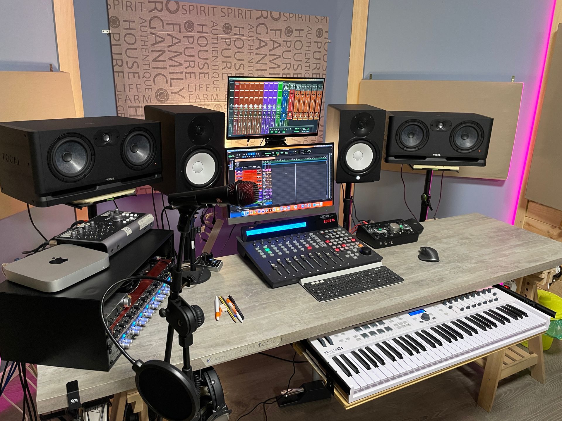 Studio musicale con console di mixaggio, monitor, tastiera e schermi di computer su una scrivania.