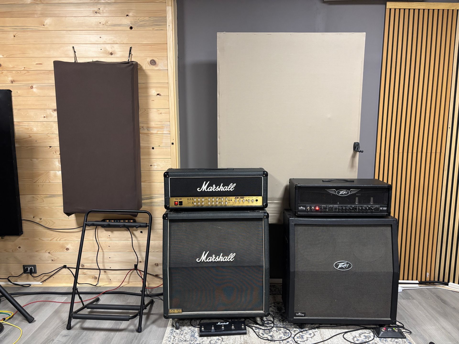 Due amplificatori per chitarra impilati su cabinet per altoparlanti in uno studio; pareti rivestite in legno e trattamento acustico.