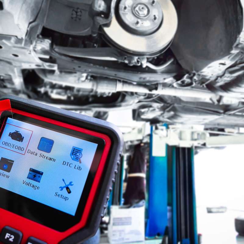 Car lifted on a service bay with a diagnostic scanner showing a blue screen in the foreground
