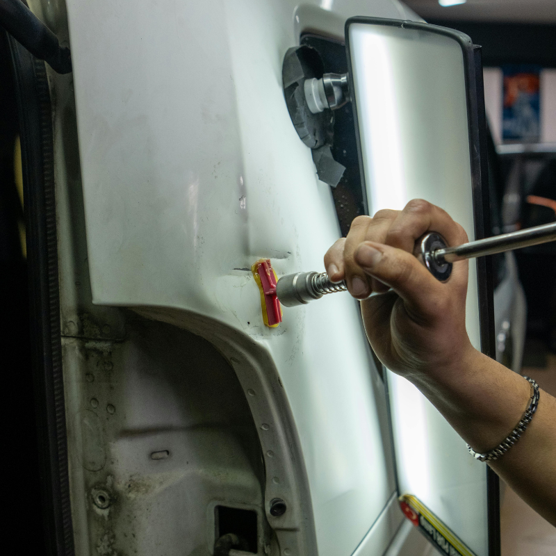 Hand polishing a white car door with a red buffing tool