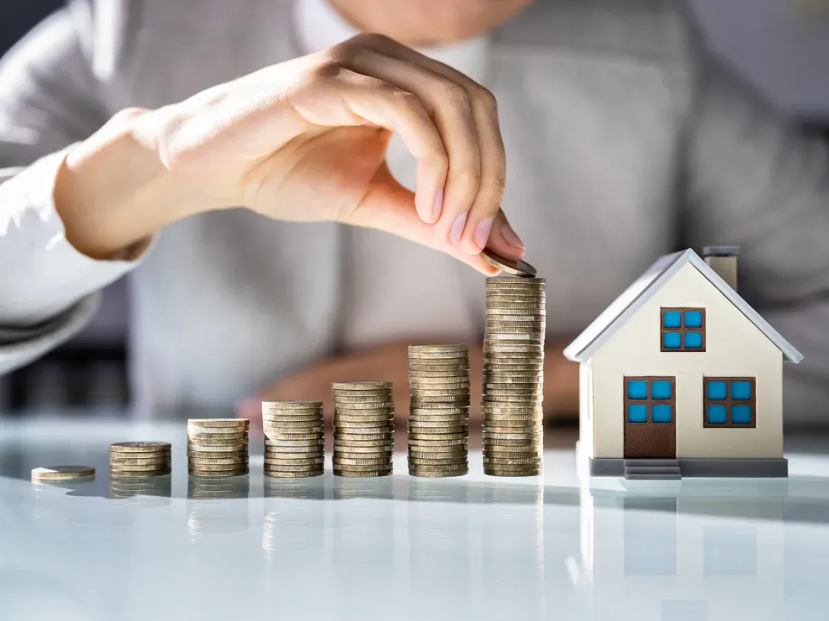A tower of coins leading to a house to represent property investment growth. A tower of coins leading to a house to represent property investment growth.