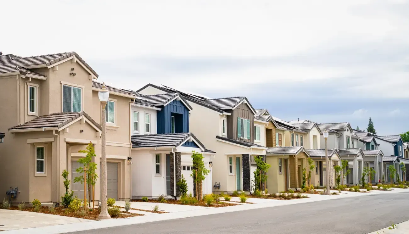 A row of houses are lined up on the side of a street. A row of houses are lined up on the side of a street.