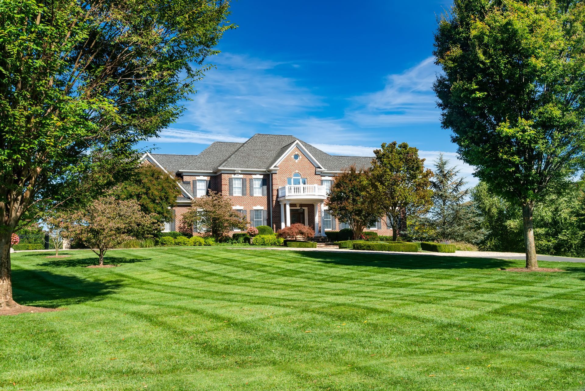 Large brick house with green lawn, blue sky, and trees. Large brick house with green lawn, blue sky, and trees.