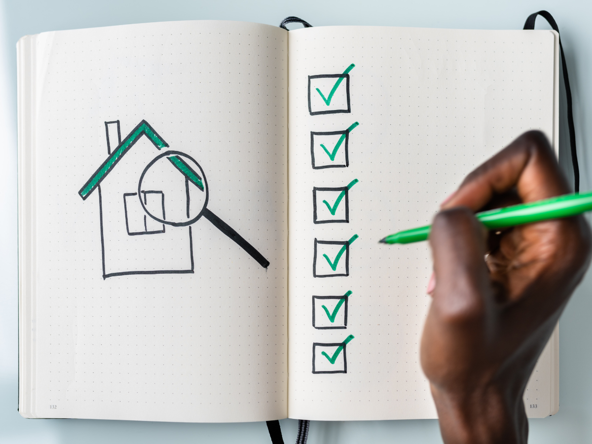 A person is drawing a house and a magnifying glass in a notebook. A person is drawing a house and a magnifying glass in a notebook.