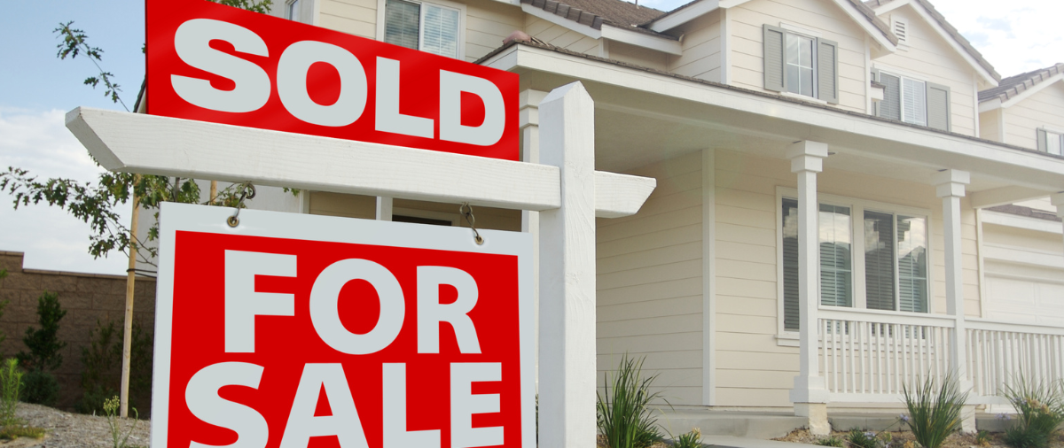 A house with two sold for sale signs in front of it. A house with two sold for sale signs in front of it.