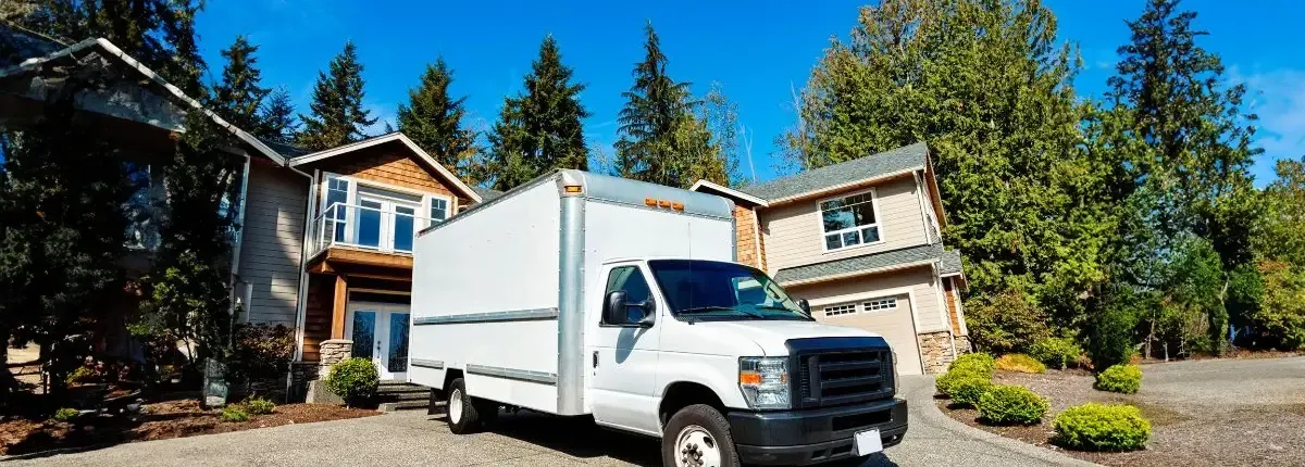 A white moving truck is parked in front of a house. A white moving truck is parked in front of a house.