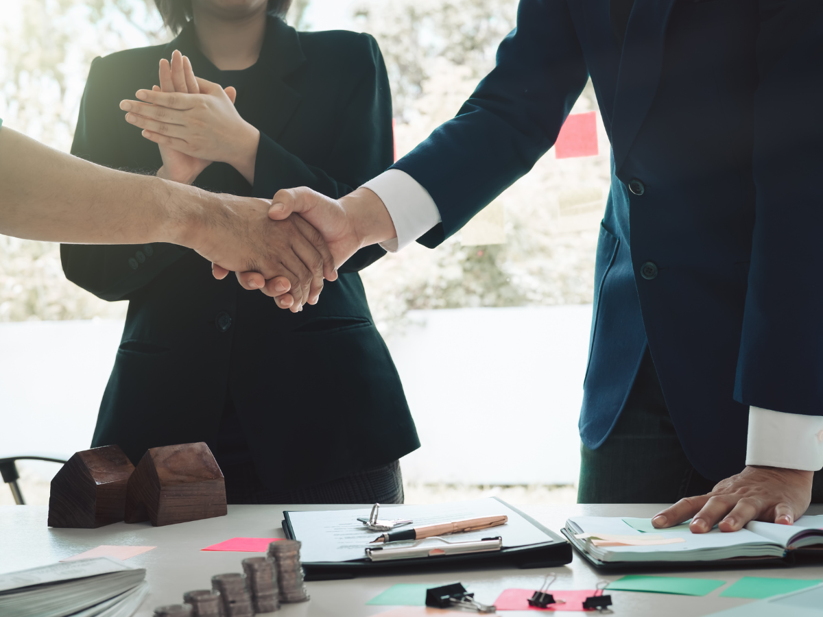 A group of business people are shaking hands over a table. A group of business people are shaking hands over a table.