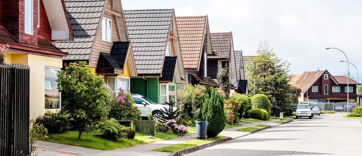 A row of houses on a residential street with cars parked on the side of the road. A row of houses on a residential street with cars parked on the side of the road.