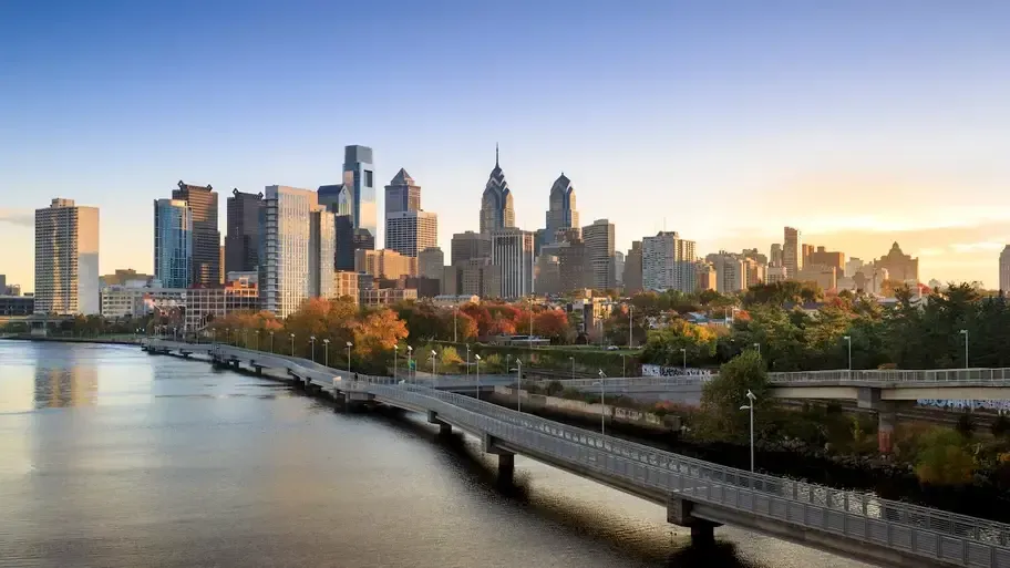 A bridge over a river with a city skyline in the background.