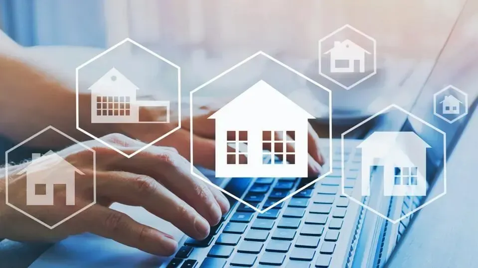 A person is typing on a laptop computer with houses on the screen. A person is typing on a laptop computer with houses on the screen.