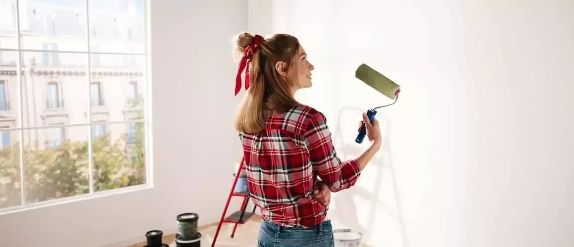 A woman painting her home so that the property value remains high.