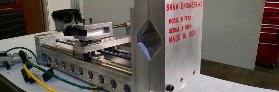 CNC milling machine in a workshop, with a silver enclosure and red warning text on the side
