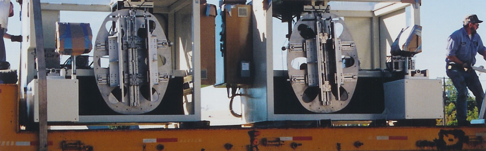 Flatbed railcar carrying large industrial machinery, with a person standing on the right side.