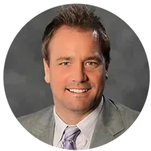 A man in a suit and tie is smiling in a circle.