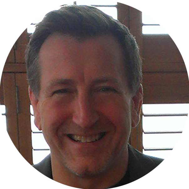 A man is smiling in a circle with shutters in the background