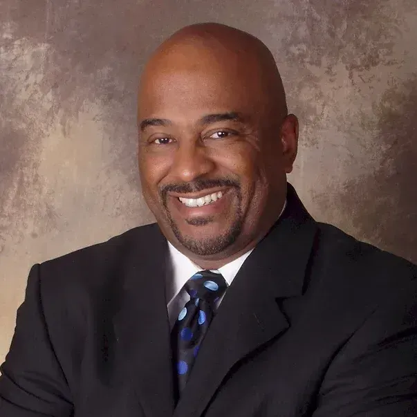 A man in a suit and tie is smiling for the camera