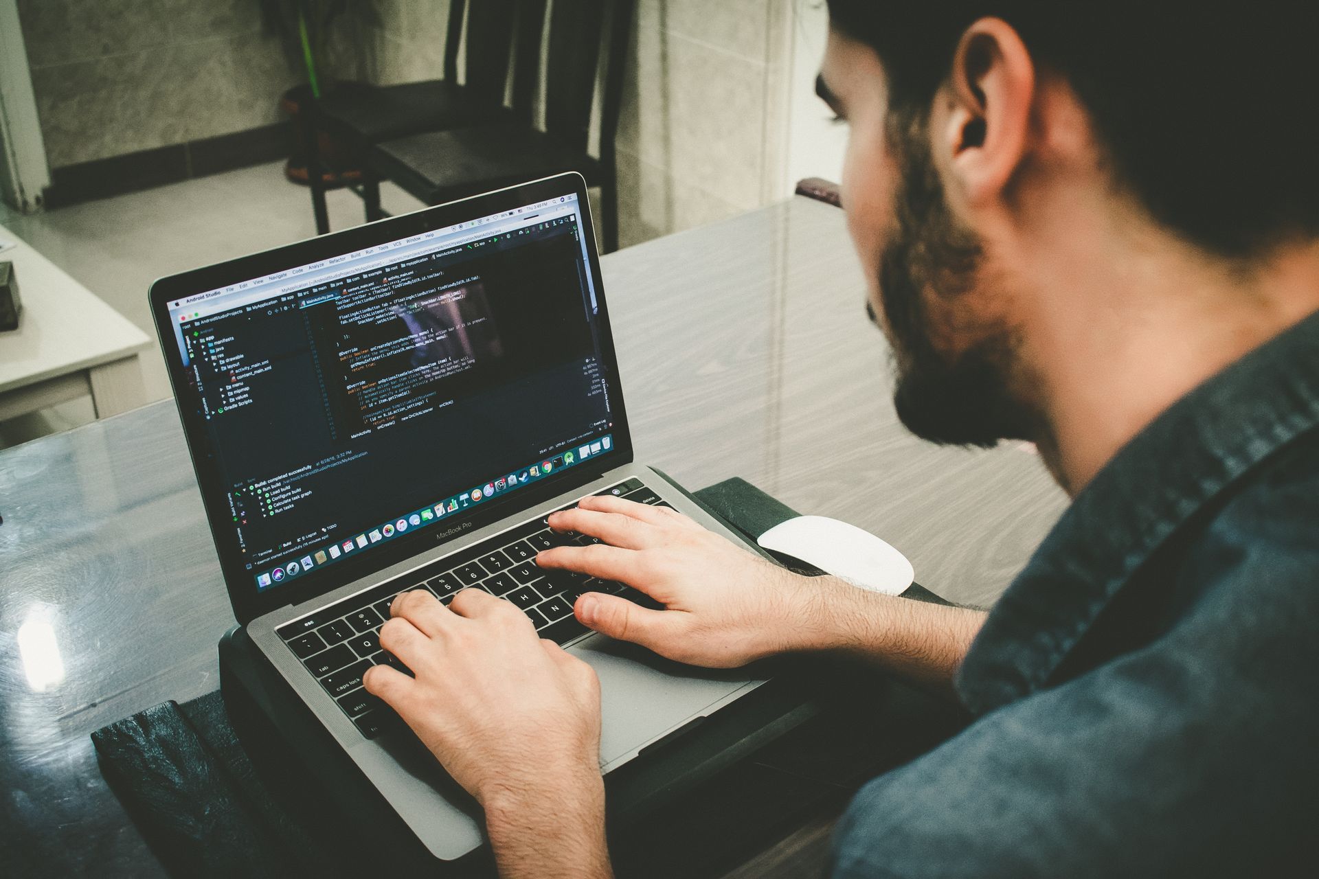 A man with a beard is typing on a laptop