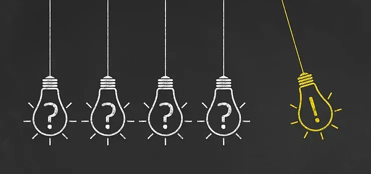 A row of light bulbs with question marks on them are hanging from a string.