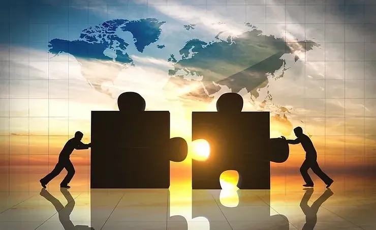 Two men are pushing puzzle pieces together in front of a map of the world.