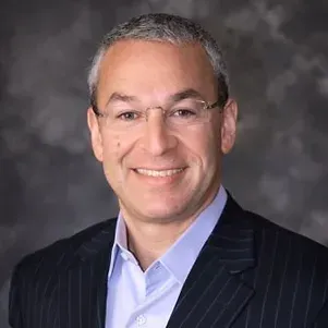 A man in a suit and glasses is smiling for the camera.