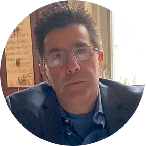 A man wearing glasses and a suit is sitting in a circle.