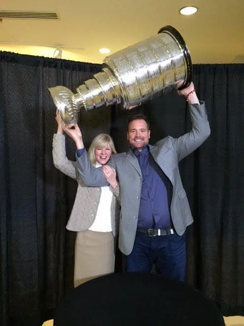 A man and woman holding up a large trophy