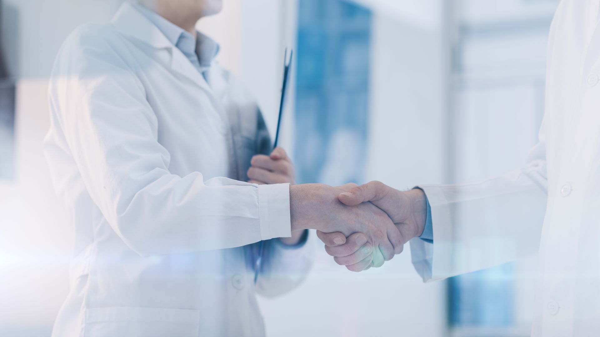 A doctor and a patient are shaking hands in a hospital.