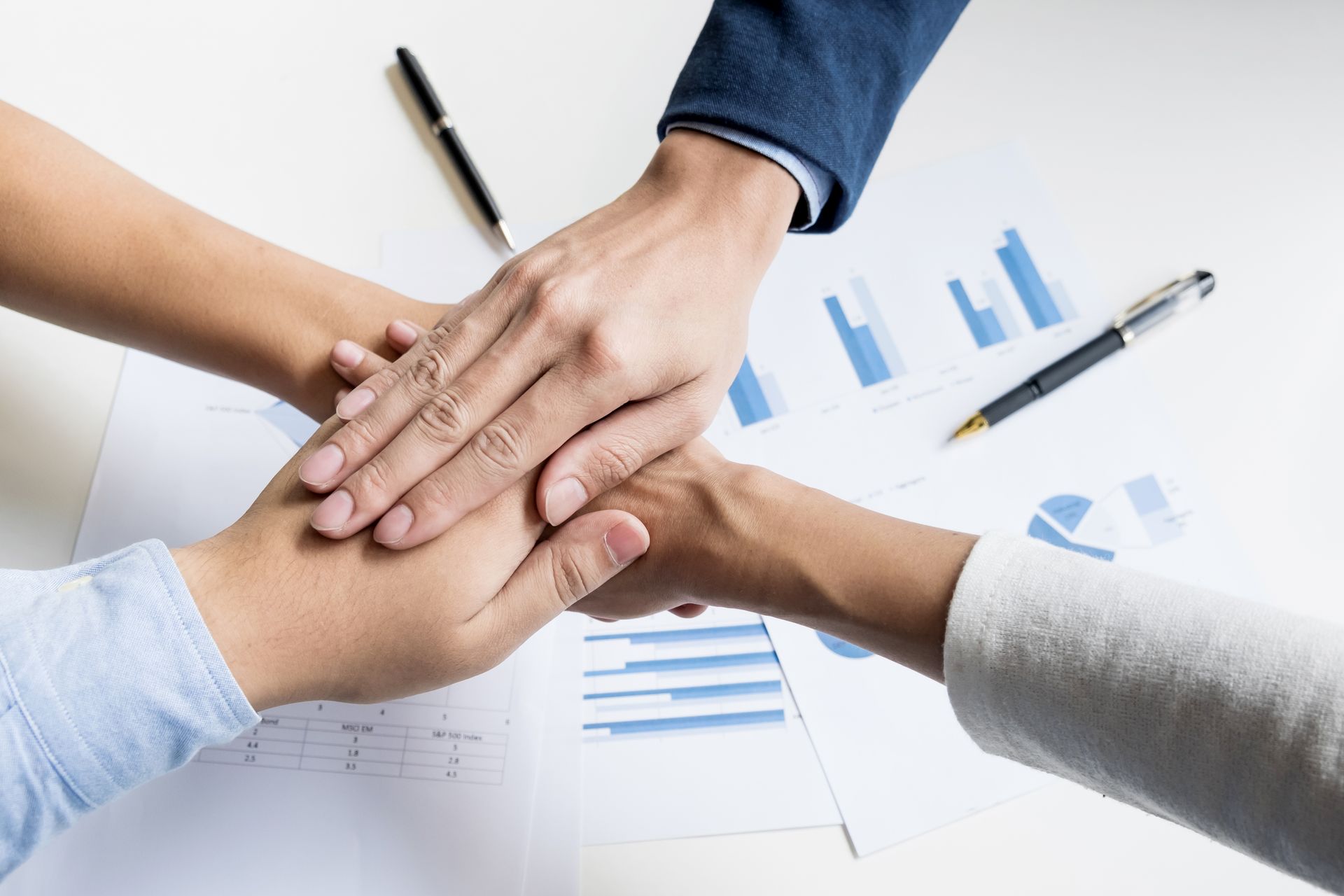 A group of people are putting their hands together on a table.