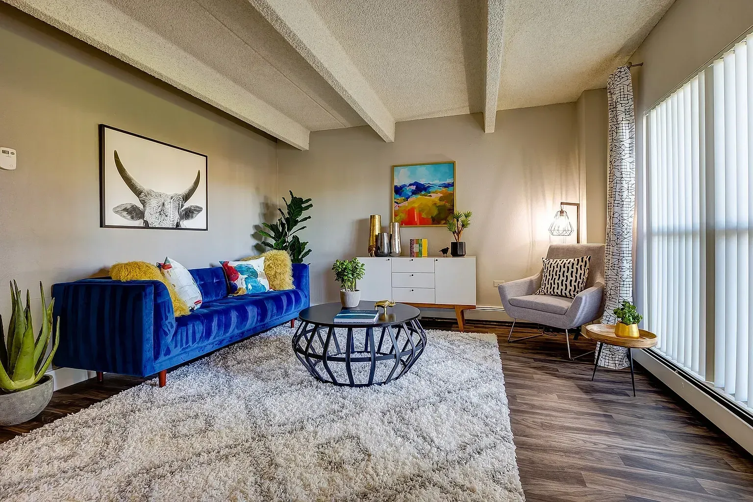 Modern living room with blue sofa, black coffee table, and abstract art.