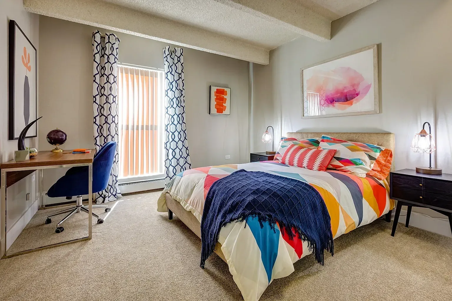 Bedroom with a colorful duvet, desk, and chair.