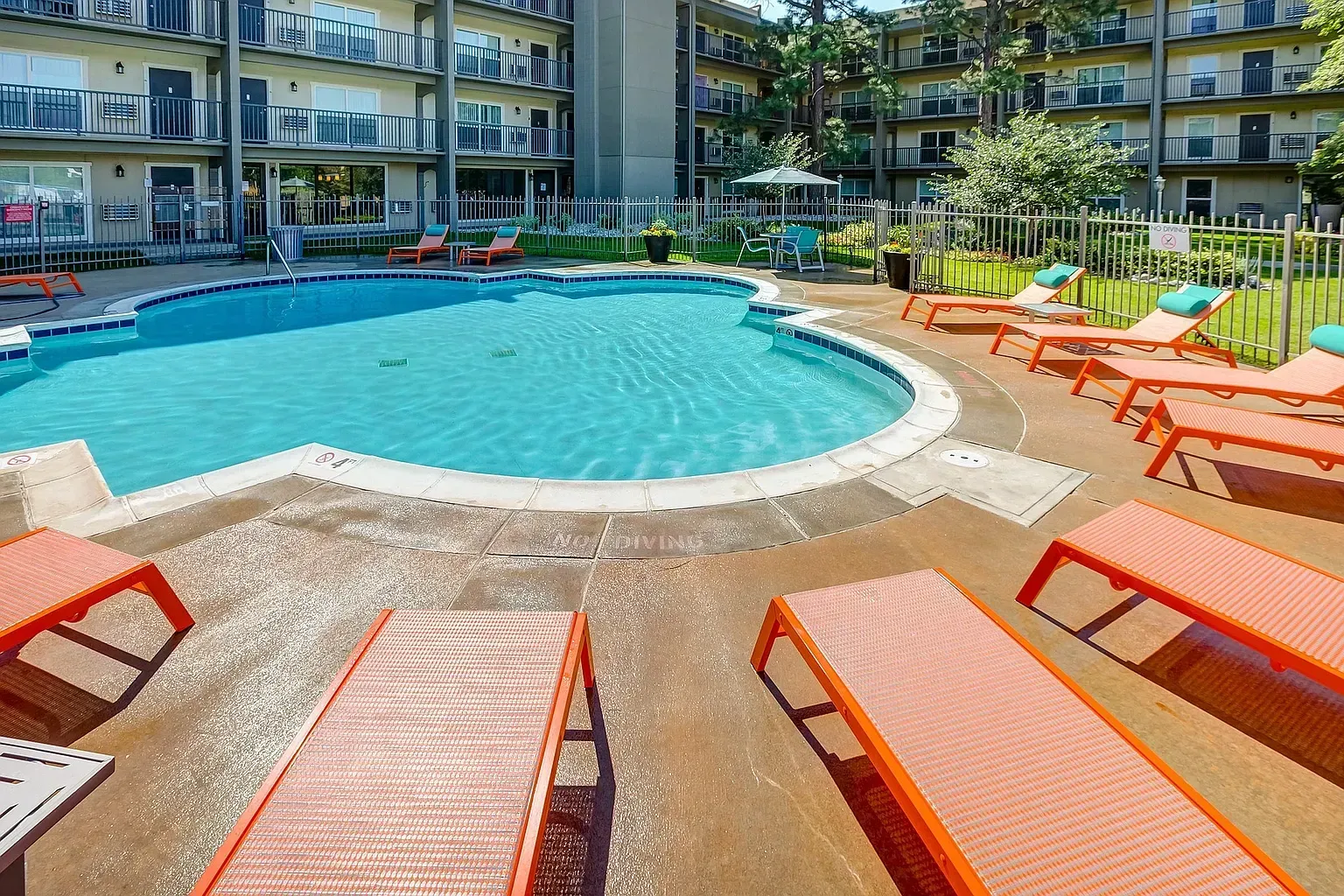 Apartment community swimming pool with lounge chairs.