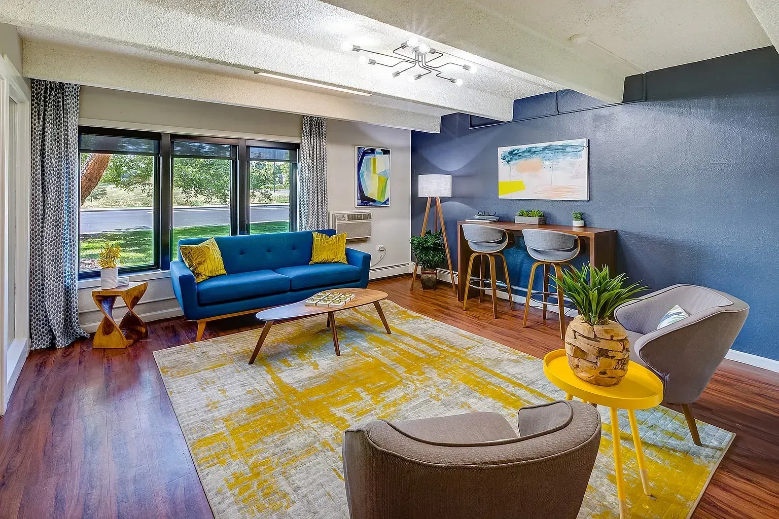 Living room with blue sofa, coffee table, rug, and bar seating.